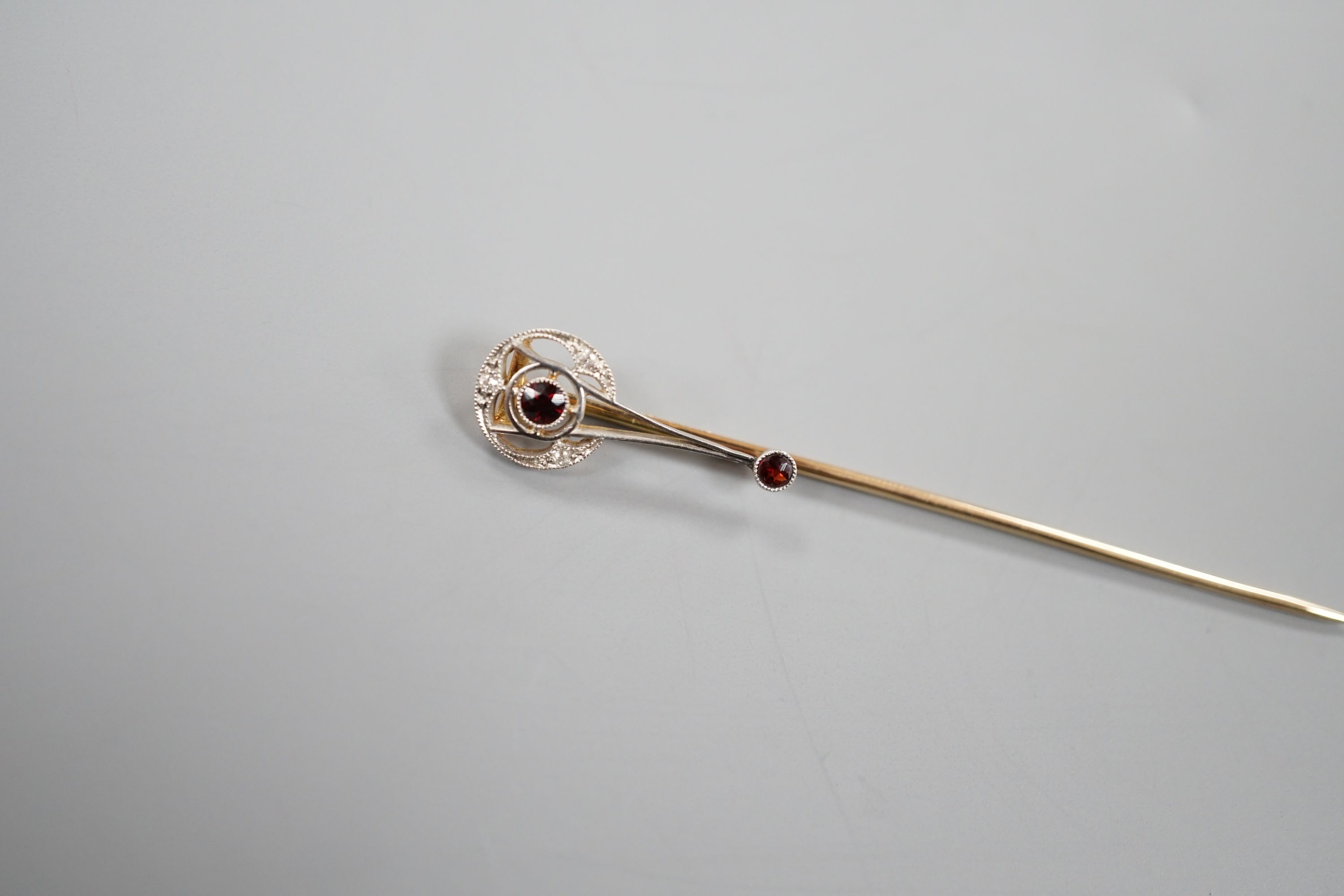 A cased American 14k, garnet and diamond chip set stick pin, by Shreeve & Company, 67mm, gross weight 2.3 grams.